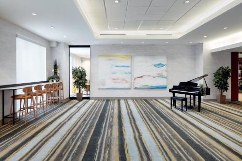 a grand piano in a room with a painting at Holiday Inn & Suites Montreal Airport by IHG in Dorval
