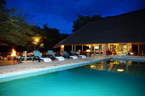 un grupo de sillas y una piscina por la noche en Timbavati Safari Lodge, en Mbabat