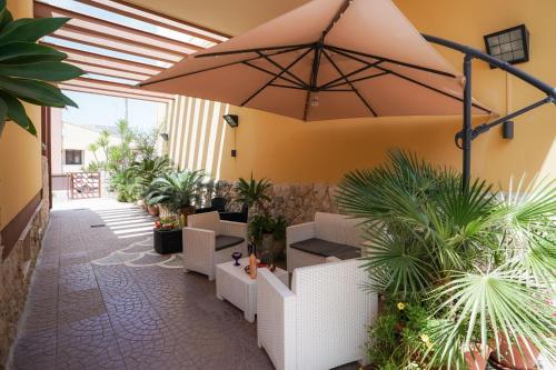 メレンドゥーニョにあるGuesthouse da Filibertoの植物と大きな傘が備わるパティオ