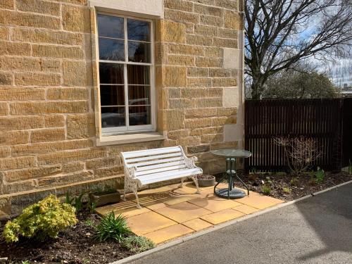 a white bench sitting in front of a brick building at Kilmorie House in Elgin