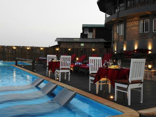 a patio with a table and chairs next to a pool at Polo Cherrapunjee Resort in Cherrapunji
