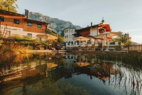 a lake with umbrellas in front of a building at Hotel Lindenhof in Ramsau am Dachstein