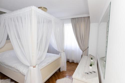 1 dormitorio con cama con dosel y cortinas blancas en ALPASIO RENTALS en Galaţi