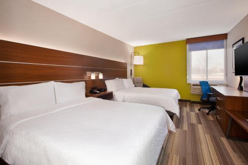 a hotel room with two beds and a desk at Holiday Inn Express Fairfax-Arlington Boulevard by IHG in Fairfax