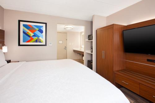 a hotel room with a bed and a flat screen tv at Holiday Inn Express Fairfax-Arlington Boulevard by IHG in Fairfax