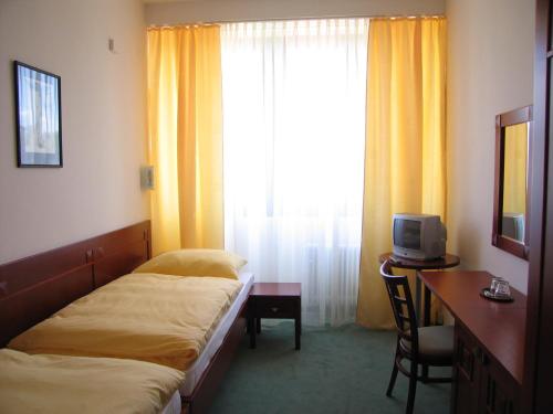 a hotel room with two beds and a desk and a window at Hotel Bothe in Považská Bystrica