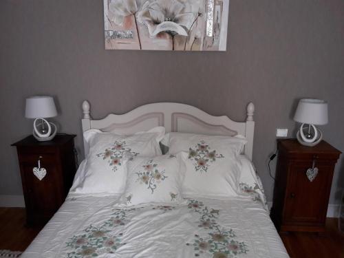 a bed with white sheets and pillows with two lamps at La maison du Mas Rando in Saint-Georges-Nigremont