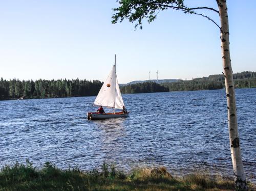 a small sail boat on a lake at Lakeview Houses Sweden - Red House in Svärdsjö