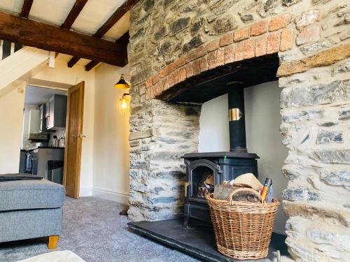 a fireplace in a living room with a stone wall at Abbey Cottage in Llangollen