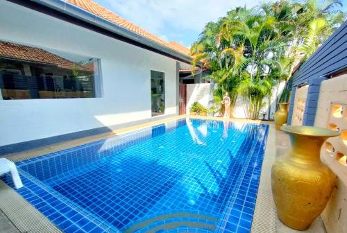 einen Pool mit blauem Fliesenboden und ein Haus in der Unterkunft CORNER VILLA - PATTAYA HOLIDAY HOUSE WALKING STREET 4 bedrooms in Pattaya South