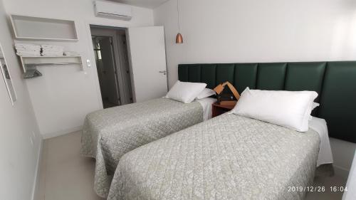 a room with two beds and a green headboard at Apartamento Espelho das Águas in Florianópolis