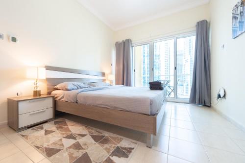 een slaapkamer met een groot bed en een groot raam bij Elegant and spacious 1bed with 2 balconies in JLT - LAKV in Dubai