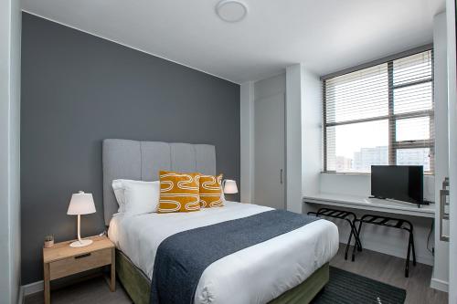 a bedroom with a bed and a desk with a television at The Median Serviced Apartment Collection in Johannesburg