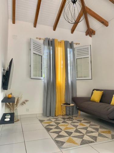 a living room with a couch and two windows at Cottage Mely’s in Rivière-Pilote