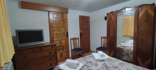 a bedroom with a tv and a bed with towels at CASA DE LOS ABUELOS in Ortigosa del Monte