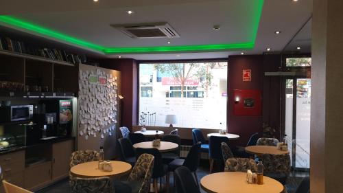 a restaurant with tables and chairs and a green ceiling at Hostal 4C Cuatro Caminos in Madrid