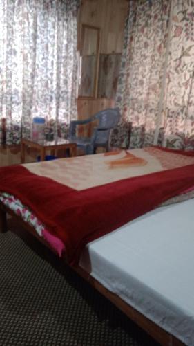 a bed with a red blanket on it in a room at Rainbow Palace Pahalgam in Pahalgām