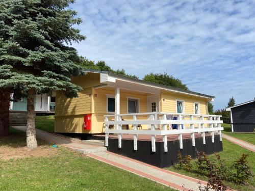 a small yellow house with a white fence at Bungalows Ostseequelle in Hohenkirchen