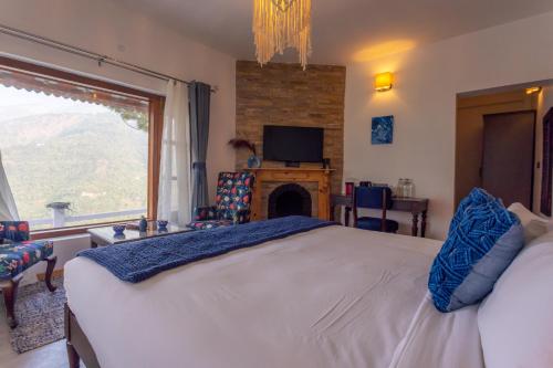 a bedroom with a large bed and a fireplace at Seclude Ramgarh Willows in Rāmgarh