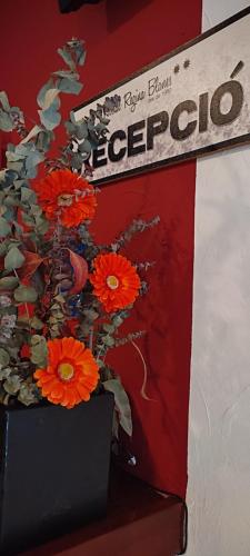 een vaas gevuld met rode bloemen op een tafel bij Hostal Regina in Blanes