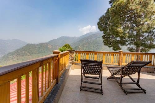 two chairs on a balcony with mountains in the background at Seclude Ramgarh Willows in Rāmgarh