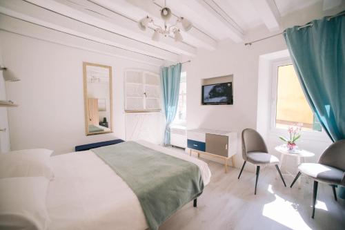 a white bedroom with a bed and a desk and chairs at Casa Cavour in Garda