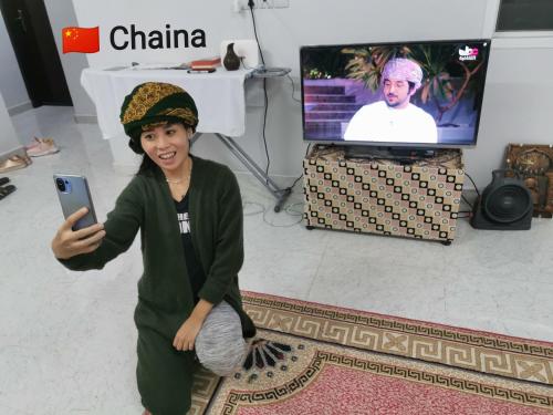 a young boy holding a cell phone in a room at 228Hostel in Al Ḩamrāʼ