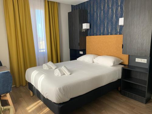 a hotel room with a large bed with white pillows at Hotel Le Cosy Riva Bella in Ouistreham