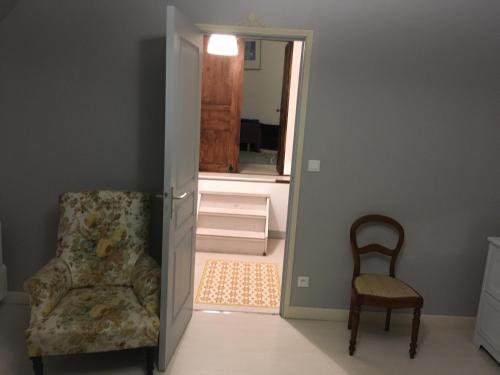 a room with a chair and a mirror and a door at La Gilberdiere in La Rochelle-Normande