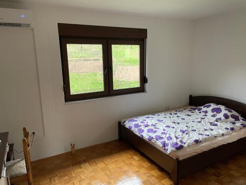 um quarto com uma cama e uma janela em Porodicna kuca za odmor Kovaci em Zavidovići