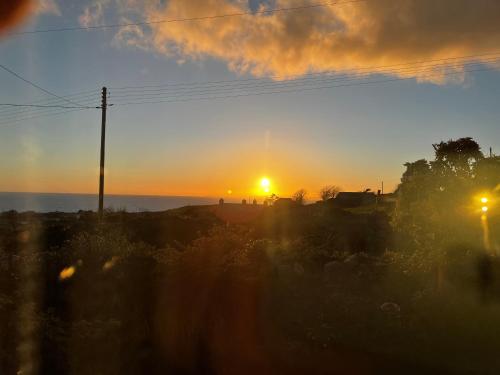 a sunset with the sun setting in the sky at Beautiful Cottage near Harlech with ocean views in Llanfair