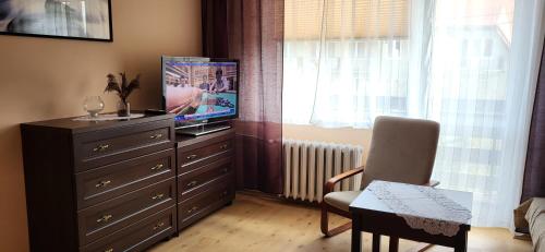 烏斯特卡的住宿－Apartament na Różanej II，客厅配有梳妆台、电视和椅子