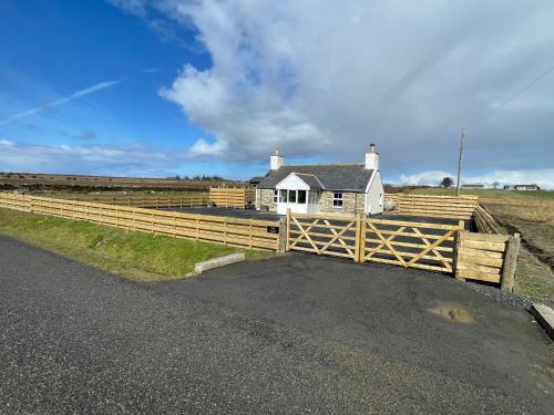 a wooden fence in front of a white house at Taigh Neonach in Watten