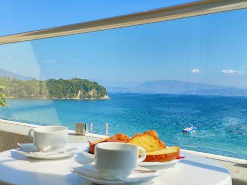 a table with toast and coffee cups and a view of the ocean at Elea Beach Hotel in Dassia