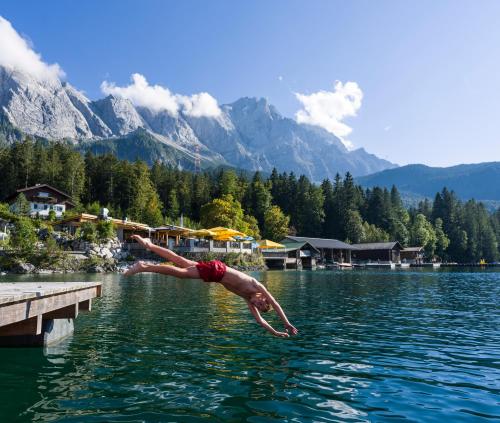 a person jumping into the water in a lake at Eibsee Hotel in Grainau
