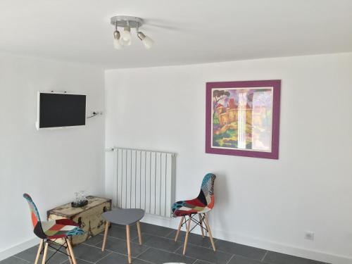 um quarto com duas cadeiras e uma mesa e uma televisão em La maison du bonheur em Cotignac