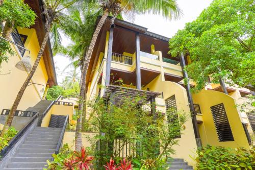 a yellow house with stairs leading up to it at Chantaramas Beach Resort Koh Phangan in Baan Khai