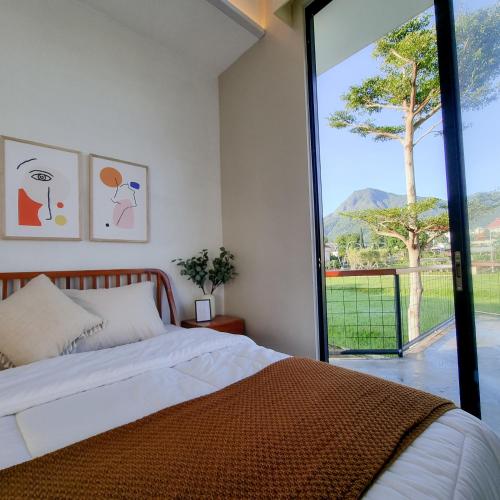 een slaapkamer met een bed en een groot raam bij Casa Terra in Batu