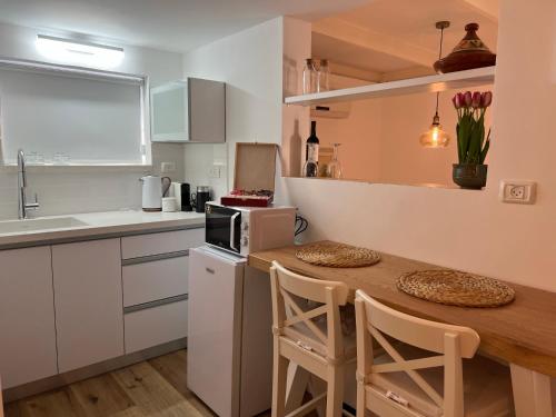 a kitchen with a wooden table with chairs and a microwave at Mango Tree Hut in Kefar H̱ittim