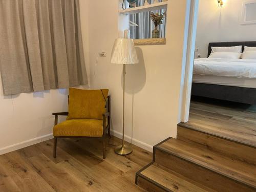 a room with a chair and a lamp and a bed at Mango Tree Hut in Kefar H̱ittim