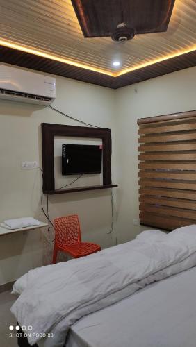 a bedroom with a bed and a red chair at Arvind Conference Halls in Jhānsi
