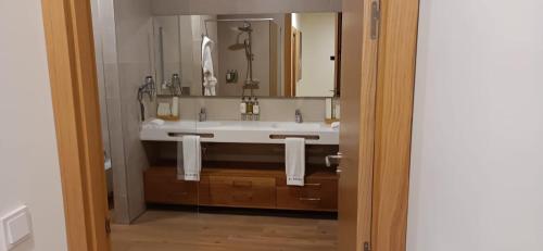 ein Badezimmer mit einem Waschbecken und einem großen Spiegel in der Unterkunft Apartamentos de lujo EL MUSEO Living&Experience Club Arte contemporáneo y mobiliario de colección de los años 50 in Málaga