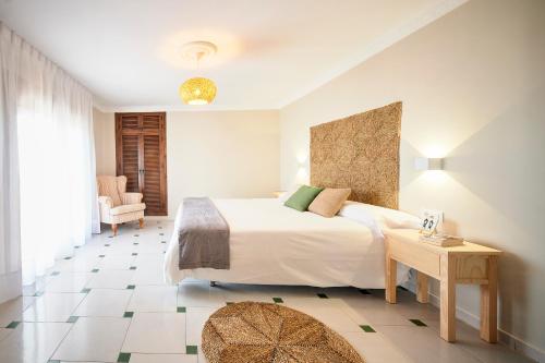 a bedroom with a large white bed and a table at La Posada Hospedería in Vejer de la Frontera