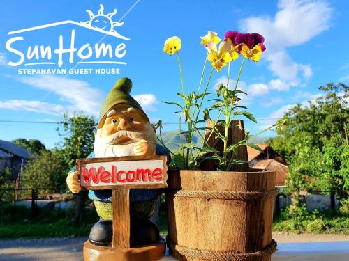 ステパナヴァンにあるSunhome Stepanavan Guest Houseの植物の隣の歓迎看板を持つ猪