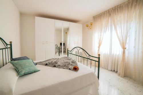 a white bedroom with a bed and a window at EUCALIPTO, splendido con terrazza panoramica sulla campagna versiliese in Massarosa
