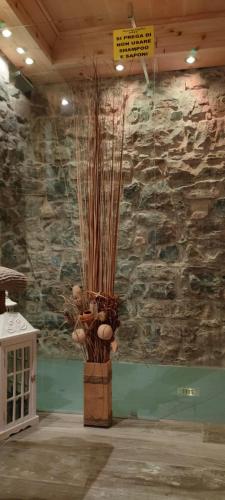 a vase filled with plants in a room with a stone wall at Haus Green & Spa Angelika Trentino in Lavarone
