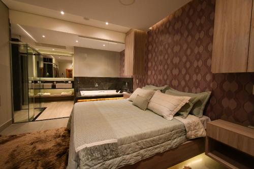 a bedroom with a large bed and a bathroom at Pousada Chão de Folhas SPA Boutique in Águas de Lindóia