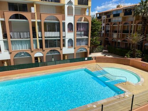 une grande piscine devant un immeuble dans l'établissement appartement T2 climatisé avec piscine secteur richelieu, au Cap d'Agde