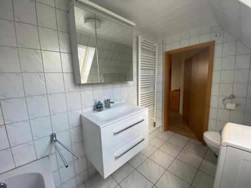 W białej łazience znajduje się umywalka i lustro. w obiekcie Ferienwohnung Schröder - 2347 w mieście Bünsdorf