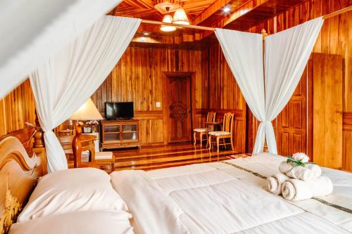 a bedroom with a bed with curtains and a television at Baan Maneekan in Sukhothai